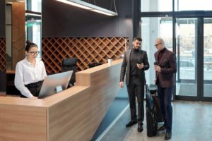 Businessmen discussing data in smartphone while receptionist using computer